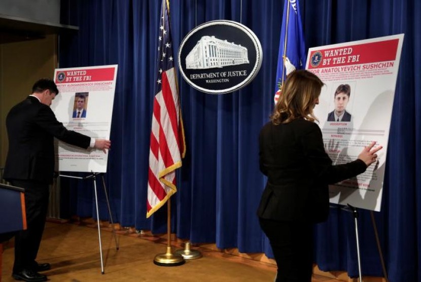 Pegawai Departemen Kehakiman AS memasang poster terduga peretas Rusia sebelum konferensi pers bersama Divisi Keamanan Nasional FBI dan Kantor Jaksa Agung di Washington, 15 Maret 2017.