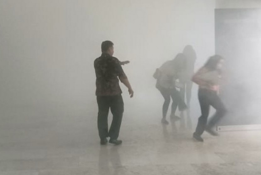 Pegawai Gedung DPR/MPR berhamburan keluar saat asap pekat muncul di Komplek Parlemen, Senayan, Jakarta, Senin (24/2).