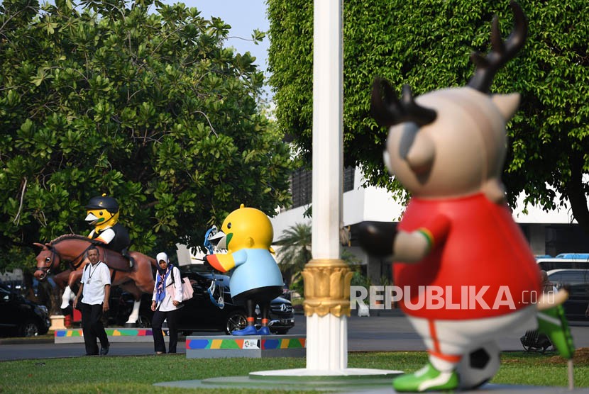 Pegawai Istana melintasi maskot Asian Games XVIII di Kompleks Istana Kepresidenan, Jakarta, Senin (14/5). 