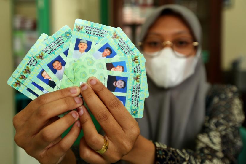 Pegawai Kantor Urusan Agama (KUA) Baiturrahman memperlihatkan kartu nikah fisik di Banda Aceh, Aceh, Kamis (9/9/2021). Kementerian Agama mulai menghentikan penerbitan kartu nikah fisik dan menggantikannya dengan kartu nikah digital guna mempermudah pasangan pengantin membawa dokumen nikah.
