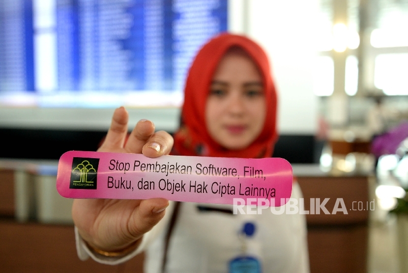 Pegawai Kementrian Hukum dan HAM menunjukan stiker saat melakukan aksi simpatik pedui kekayaan intelektual di Bandara Soekarno-Hatta, Taggerang, Banten, Kamis (20/10).