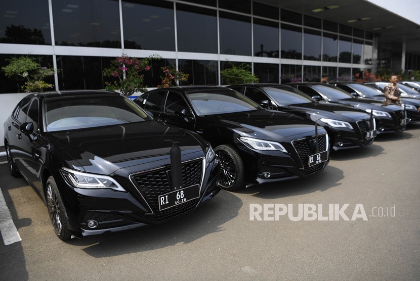 Pegawai melintasi deretan kendaraan dinas pimpinan parlemen, Toyota Crown 2.5 HV G-Executive di Kompleks Parlemen, Senayan, Jakarta, Selasa (29/10/19). 