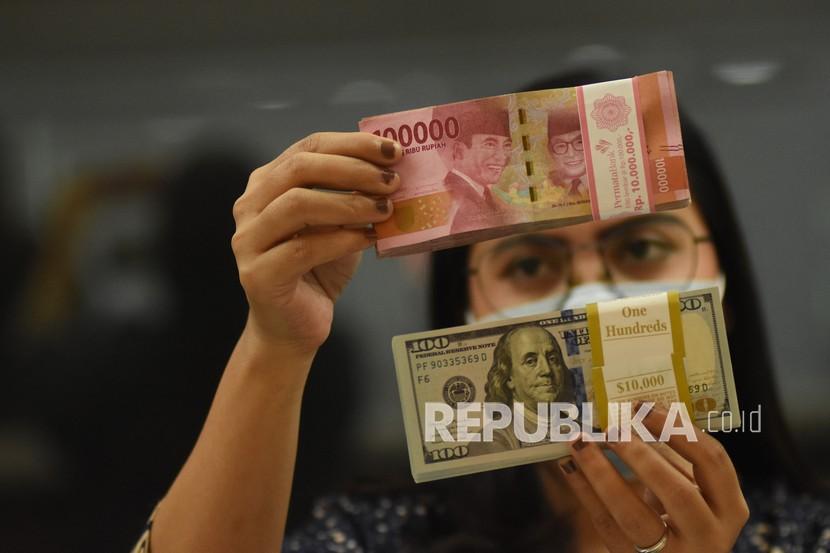 Pegawai menunjukkan mata uang rupiah dan dolar AS di salah satu gerai penukaran mata uang (ilustrasi). Nilai tukar (kurs) rupiah yang ditransaksikan antarbank di Jakarta pada Kamis (22/9/2022) sore melemah. Rupiah ditutup melemah 26 poin atau 0,17 persen ke posisi Rp15.023 per dolar AS