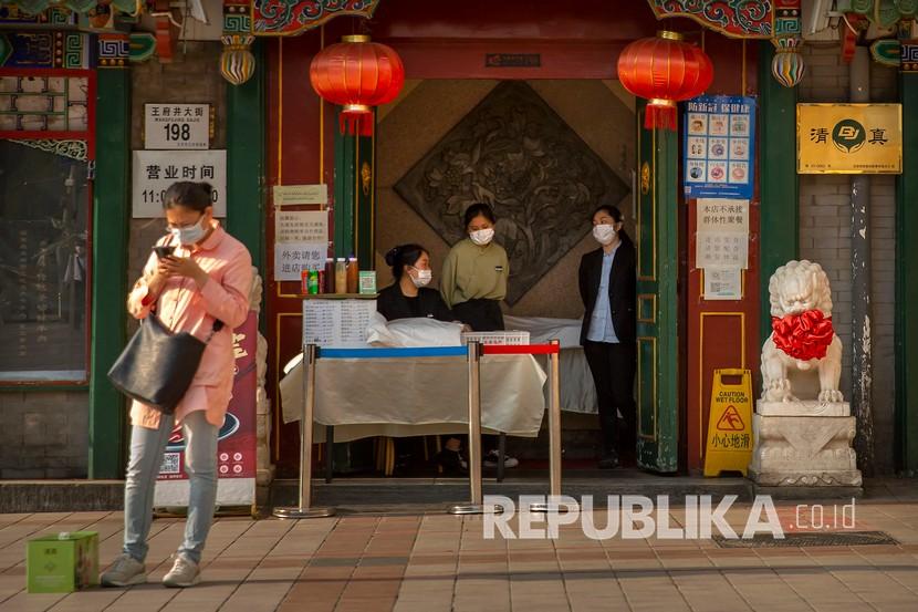 Pegawai toko mengenakan masker untuk mencegah penyebaran virus Corona saat menunggu pelanggan di pintu masuk sebuah restoran di Beijing, Selasa (28/4). 