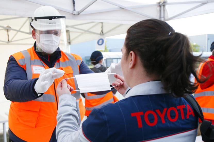 Pegawai Toyota memperagakan cara memakai masker. Toyota mengatakan akan menunda dimulainya kembali operasi manufaktur di Amerika Utara hingga 11 Mei