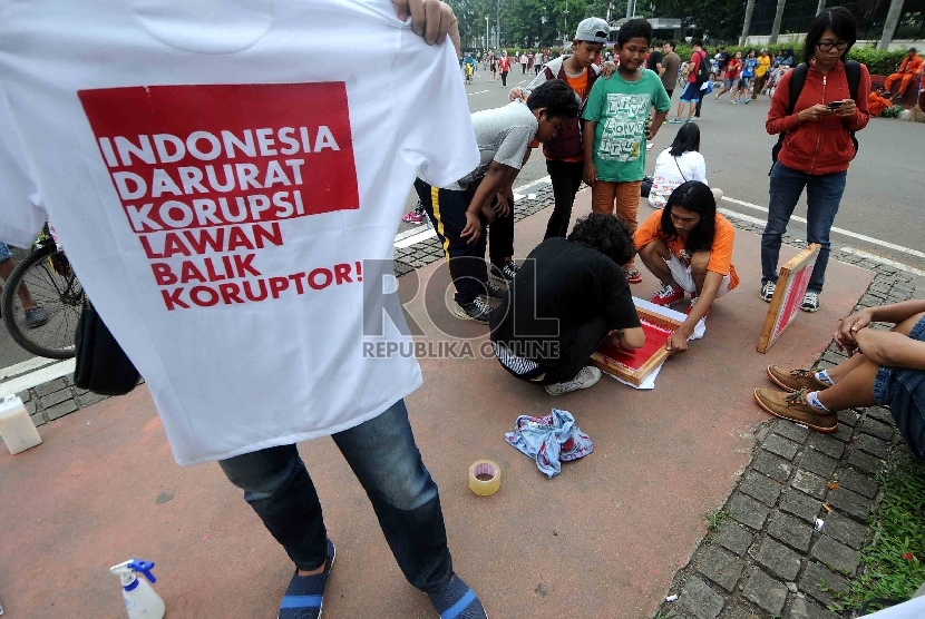 Pegiat anti korupsi memberikan layanan sablon kaos gratis anti korupsi kepada warga saat Hari Bebas Kendaraan Bermotor di Bundaran HI, Jakarta, Ahad (15/2).    (Republika/Agung Supriyanto)