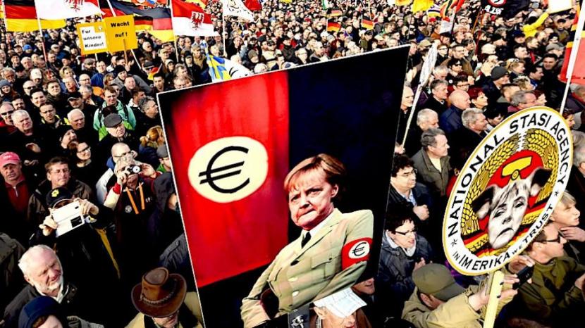 Pegida, kelompok Anti Muslim Jerman mengusung psoter kanselir Angela Merkel dengan pakain bergaua Hitler.
