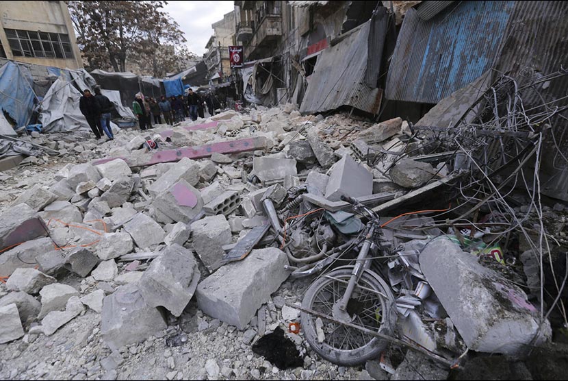 Warga  memperhatikan gedung yang hancur akibat serangan udara pasukan pemerintah Suriah di Kota Ariha, Provinsi Idlib Suriah, Rabu (15/1).