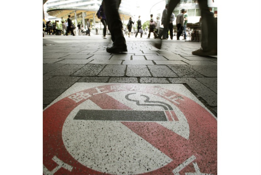   Pejalan kaki berjalan dekat tanda larangan merokok di Tokyo, Jepang, Kamis (31/5).(Shizuo Kambayashi/AP)