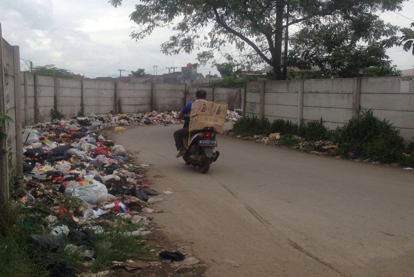 Pejalan kaki dan pengendapan motor melewati sampah yang menumpuk di jalur masuk Terminal Baleendah, Selasa (1/2).