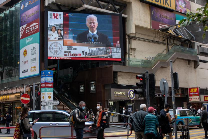 Pejalan kaki di Hong Kong, China, melewati layar yang memperlihatkan inaugurasi Presiden AS Joe Biden, Kamis (21/1). Hubungan AS dan China di bawah kepemimpinan Biden diduga tetap akan penuh ketegangan. 