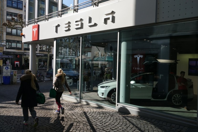 Pejalan kaki melewati gerai mobil Tesla di Jerman.