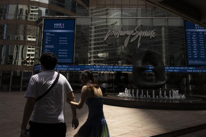 Pejalan kaki melewati layar elektronik Bursa Efek Hong Kong di Hong Kong, Rabu, 21 Juni 2023.