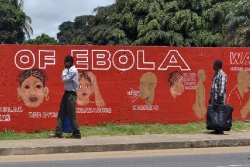 Pejalan kaki melewati mural yang memperlihatkan gejala ebola.