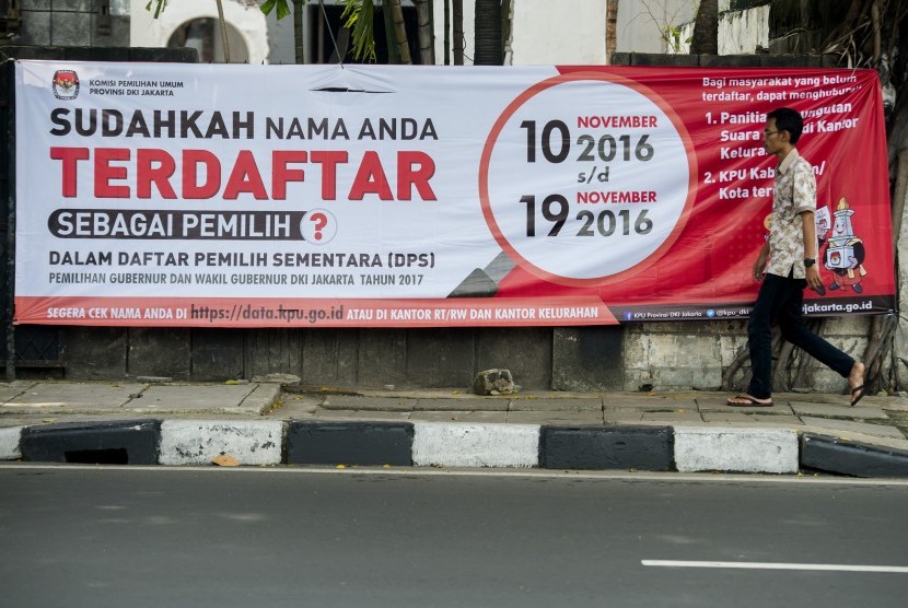 Pejalan kaki melintas di depan spanduk sosialisasi Daftar Pemilih Sementara (DPS) Pemilihan Gubernur dan Wakil Gubernur DKI Jakarta Tahun 2017 di Jalan Cikini Raya, Jakarta Pusat, Senin (14/11). 