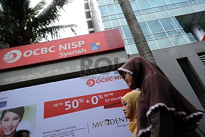  Pejalan kaki melintas dibalik signed Bank Syariah di Jakarta, Kamis (10/9). 