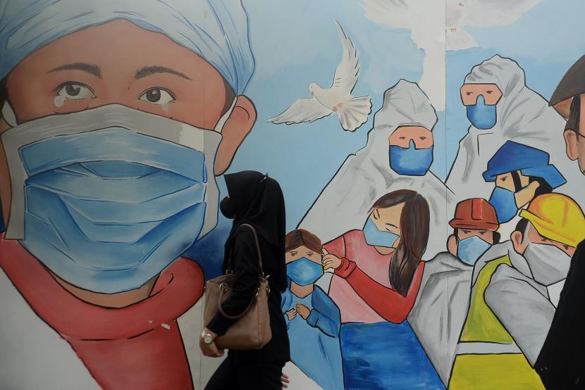 Pejalan kaki melintas didekat mural bertema Covid-19 dikawasan Lapangan Bhayangkara, Jakarta.  Pada Sabtu (22/1/2022), kasus Covid-19 di Indonesia mengalami penambahan 3.205.