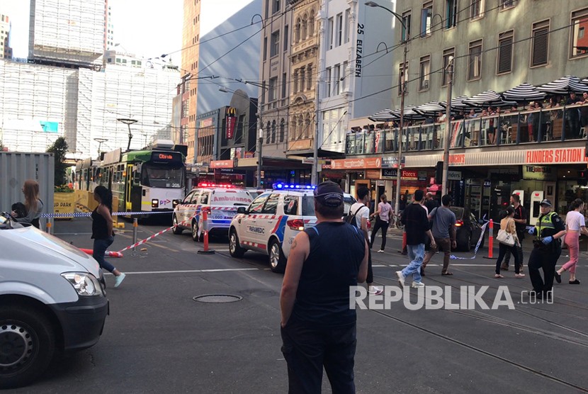 Pejalan kaki melintas saat polisi tiba di lokasi kejadian kendaraan yang menabrak pejalan kaki di Melbourne, Kamis (21/12). 