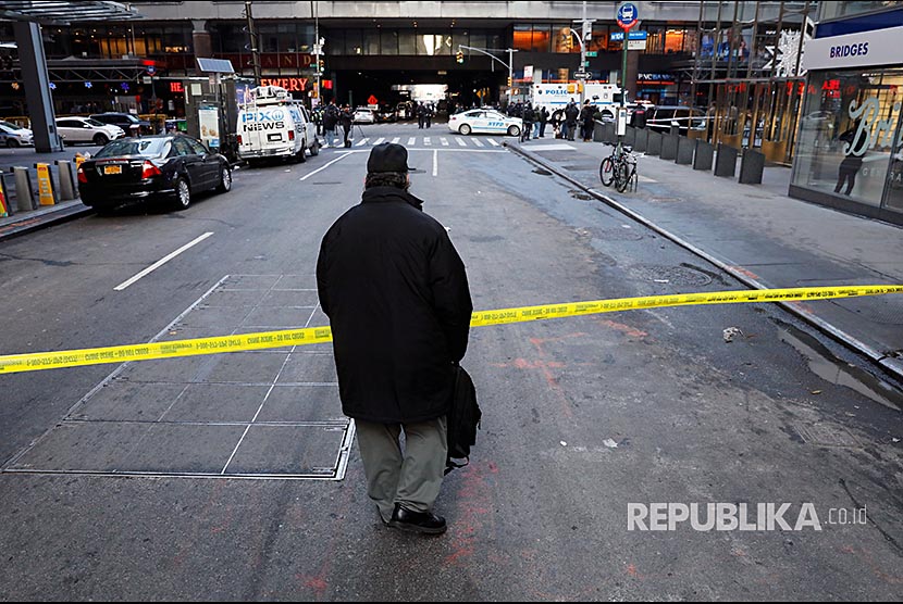 Pejalan kaki melintasi batas polisi yang dipasang di terminal bus New York City  Senin (11/12) waktu setempat.