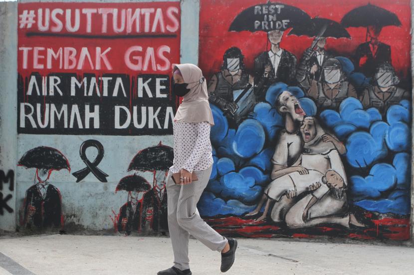 Pejalan kaki melintasi mural bertema tragedi Kanjuruhan di Jalan Basuki Rahmat, Malang, Jawa Timur.