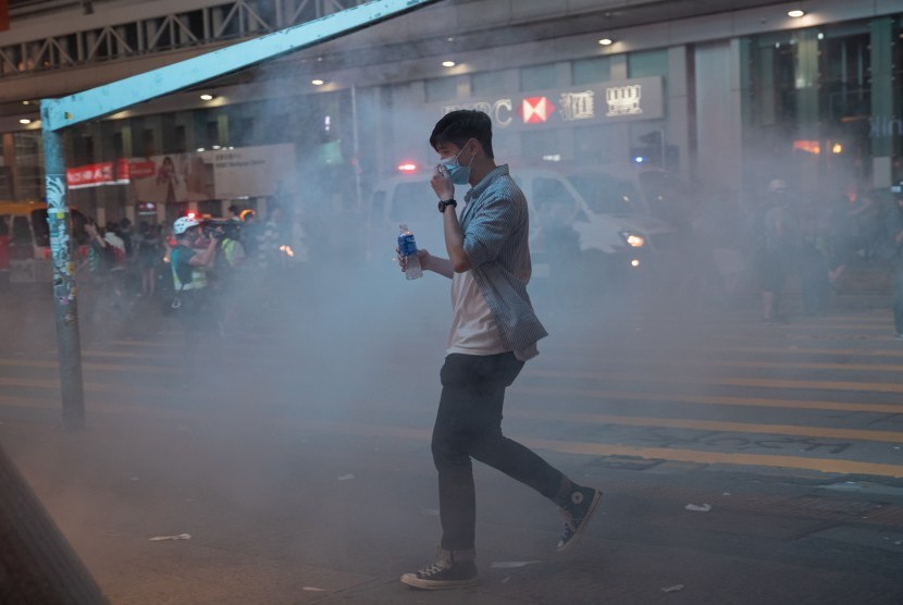 Pejalan kaki terperangkap dalam awan gas air mata yang ditembakkan oleh polisi anti-huru hara setelah demonstrasi menentang kebrutalan polisi dan untuk berdiri bersama Muslim dan wartawan di Hong Kong, Cina, 27 Oktober 2019. 