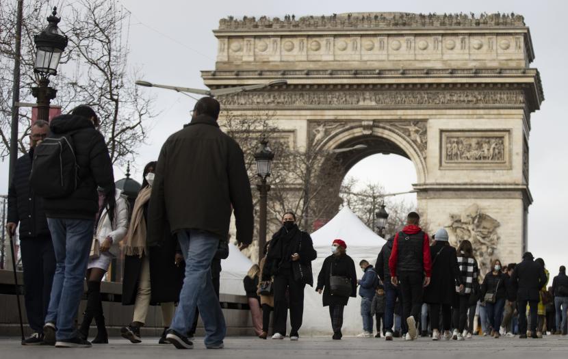 Pejalan kaki yang mengenakan masker berjalan di Champs-Elysees di pusat kota Paris, Prancis, 30 Desember 2021. Jumlah kasus COVID-19 baru melonjak melewati 200.000 per hari, mendorong kota Paris untuk memberlakukan kembali kewajiban mengenakan masker di luar ruangan pada 31 Desember. 