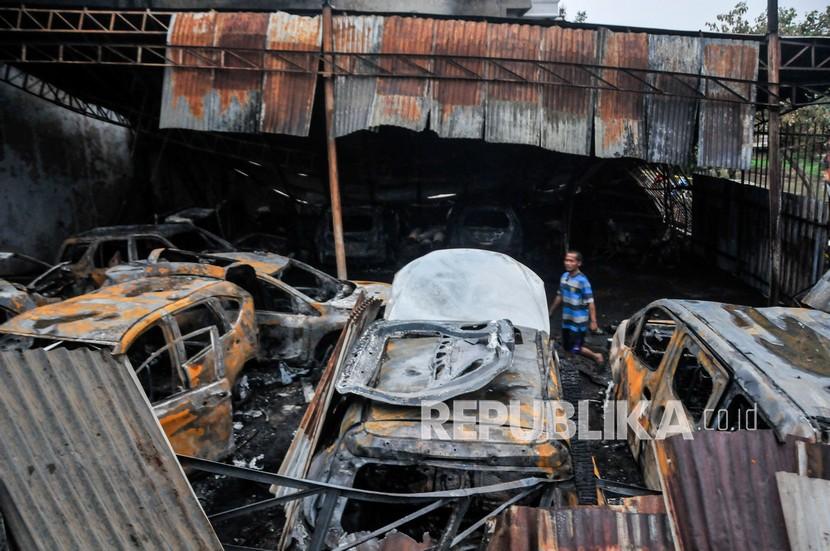 Pekerja berada di dekati mobil yang rusak usai kebakaran bengkel reparasi di Duren Sawit, Jakarta Timur. (ilustrasi)