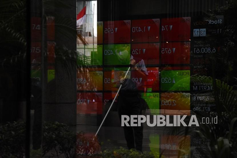 Pekerja beraktivitas di dekat refleksi layar indeks harga saham di Bursa Efek Indonesia, Jakarta, Jumat (11/2/2022). Indeks Harga Saham Gabungan (IHSG) pekan ini mencapai rekor tertinggi sepanjang masa, yaitu pada posisi 6.892,818.