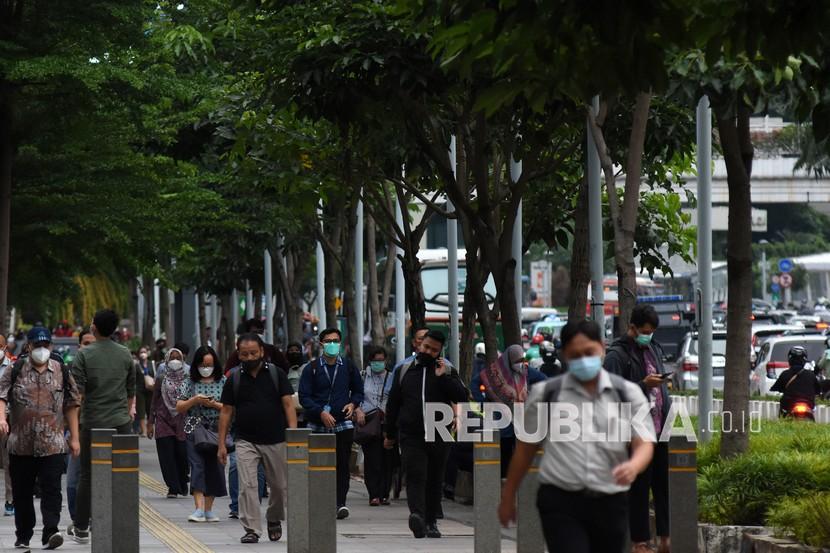 Pekerja berjalan di trotoar Jalan Jenderal Sudirman saat jam pulang kerja di Jakarta, Rabu (17/11/2021).
