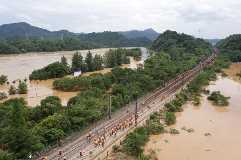 Pekerja berkumpul di sepanjang bagian rel kereta api yang banjir di Shangrao di provinsi Jiangxi, China tengah, Selasa, 21 Juni 2022. Banjir besar telah memaksa evakuasi puluhan ribu orang di China selatan, dengan curah hujan lebih tinggi diperkirakan akan turun.