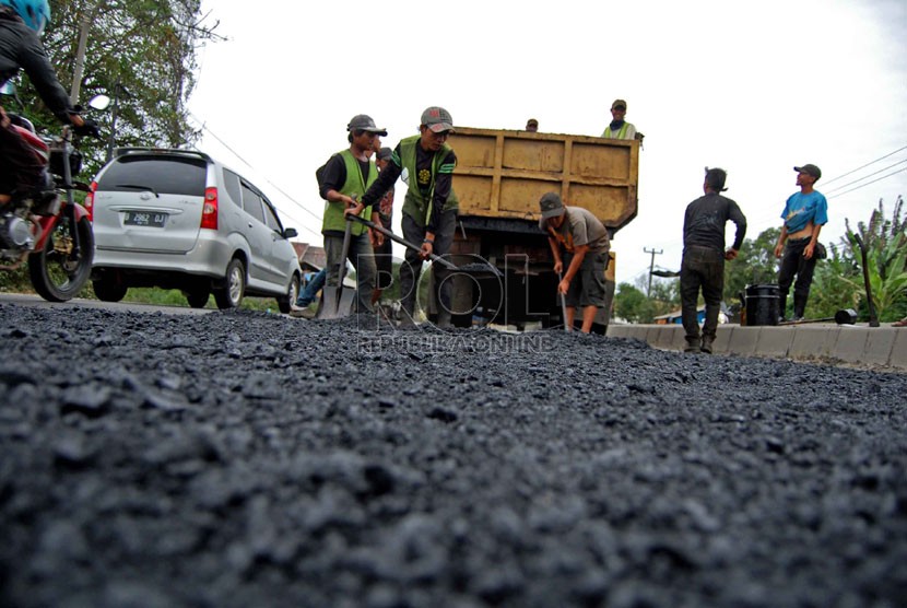  Pekerja dari Dinas Jasa Marga Provinsi Jawa Barat menyelesaikan penambalan jalan, Jalur Pantura, Indramayu, Jawa Barat, Selasa (8/7). (Republika/Raisan Al Farisi)