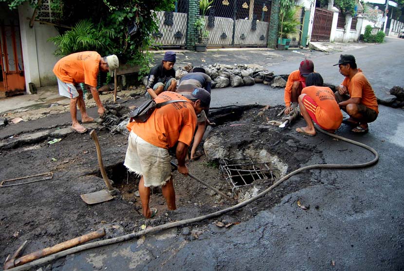 Pekerja dari Suku Dinas Tata Air Jakarta Timur memperbaiiki jalan yang amblas di Jalan Cipinang Cempedak IV, Jakarta Timur, Senin (16/6). 