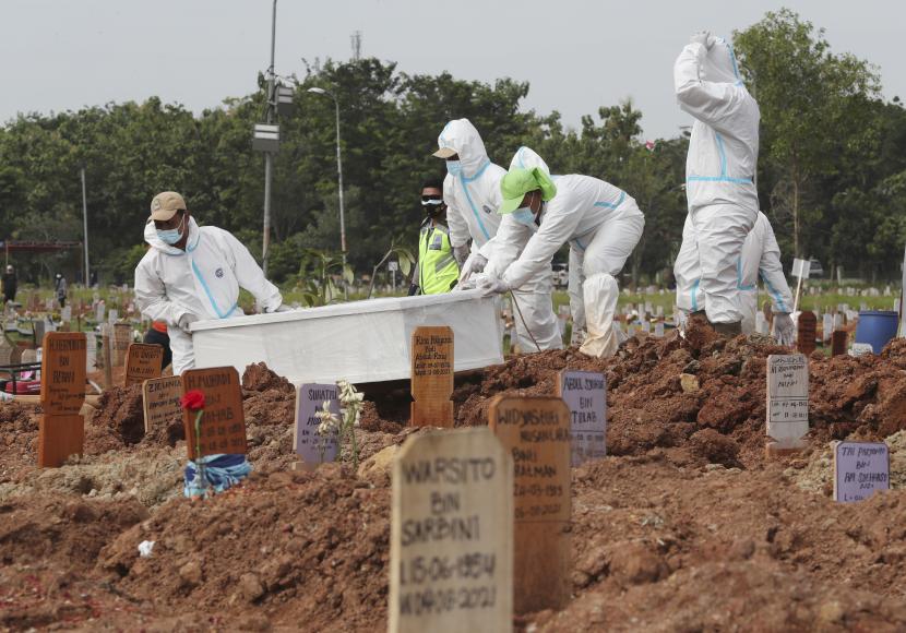 Pekerja dengan alat pelindung diri menurunkan peti jenazah korban COVID-19 untuk dimakamkan di bagian khusus pemakaman Pedurenan yang ditunjuk untuk menampung lonjakan kematian selama wabah virus corona di Bekasi, Jawa Barat, Indonesia, Kamis, 12 Agustus 2021.