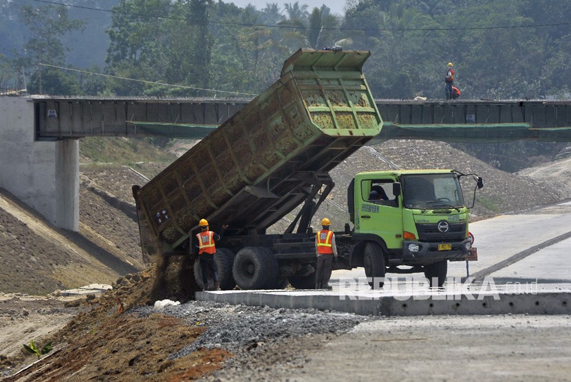 Pekerja dengan menggunakan alat berat mengurug bahu jalan di lokasi proyek Jalan Tol Serang - Panimbang. ilustrasi