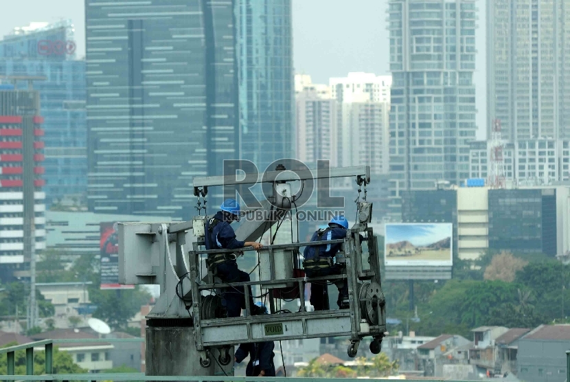Pekerja dengan perlengkapan keselamatan kerja membersihkan dinding gedung bertingkat di Jakarta, Rabu (29/7). 