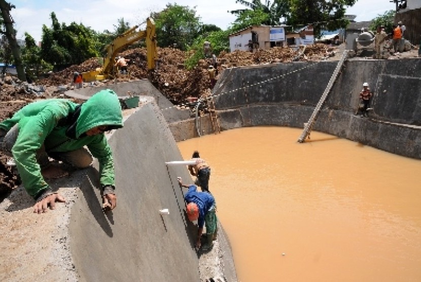 Pekerja dibantu alat berat menyelesaikan pembuatan waduk resapan air di Jalan Merdeka, Depok, Jawa Barat, Sabtu (21/12). Pembuatan waduk resapan tersebut guna membantu mengurangi daerah genangan banjir di kota Depok sekaligus menjadi sumber air bagi Dinas 