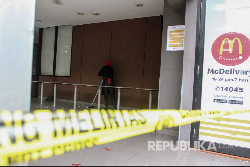 Pekerja gerai makanan siap saji Mc Donalds membersihkan halaman samping yang terpasang garis polisi di Kota Pekanbaru, Riau, Rabu (9/6/2021). Satgas COVID-19 Kota Pekanbaru menyegel untuk sementara gerai McDonald