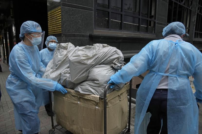 Pekerja hotel mengenakan alat pelindung diri, membawa sampah dari hotel isolasi di Hong Kong, Sabtu, 2 April 2022.