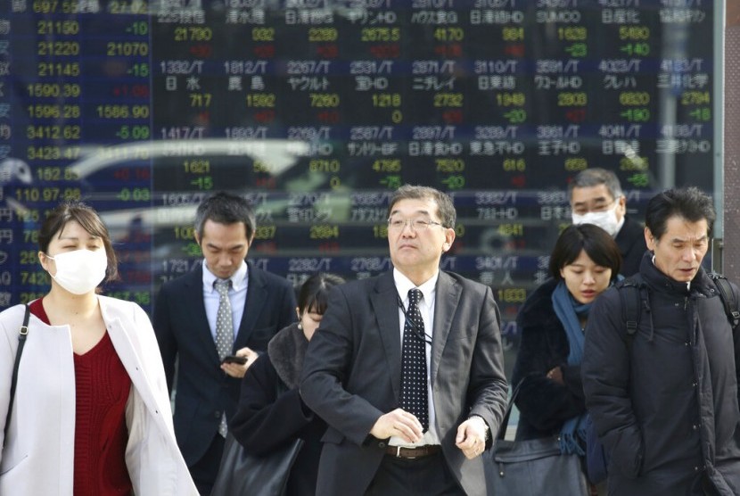 Pekerja Jepang melintas di depan monitor pergerakan harga saham milik sebuah perusahaan sekuritas. Ekonomi Jepang mengalami rebound 1,4 persen.