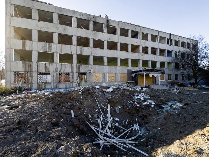 Pekerja kota membersihkan puing-puing di atap Universitas No. 47 yang rusak akibat serangan roket Rusia di Kramatorsk, Ukraina, Senin, 9 Januari 2023.