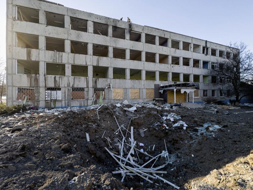 Pekerja kota membersihkan puing-puing di atap Universitas No. 47 yang rusak akibat serangan roket Rusia di Kramatorsk, Ukraina, Senin, 9 Januari 2023.