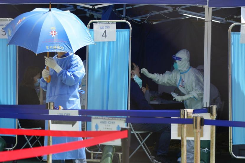 Pekerja medis membantu warga menjalani tes virus corona di pusat pengujian sementara di Hong Kong, Senin, 14 Maret 2022. Hong Kong akan menghapus beberapa pembatasan COVID-19, termasuk tes PCR untuk pelancong yang datang dan persyaratan vaksinasi untuk memasuki tempat-tempat tertentu , kata pemimpin kota itu Rabu, 28 Desember 2022.