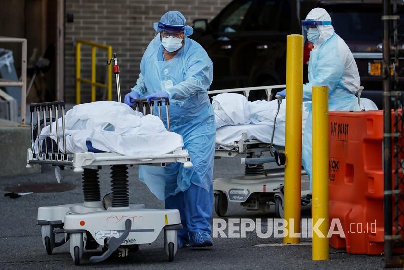 Pekerja medis mengenakan alat pelindung diri membawa jasad korban Covid-19 menuju kamar jenazah darurat di Wyckoff Heights Medical Center, New York, Senin (6/4). New York menghadapi hari paling mematikan pada Selasa.