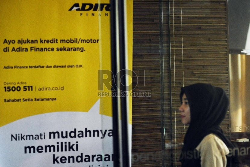  Pekerja melintas berlatar belakang penyaluran kredit Adira Finance di Jakarta, Jumat (21/8). 