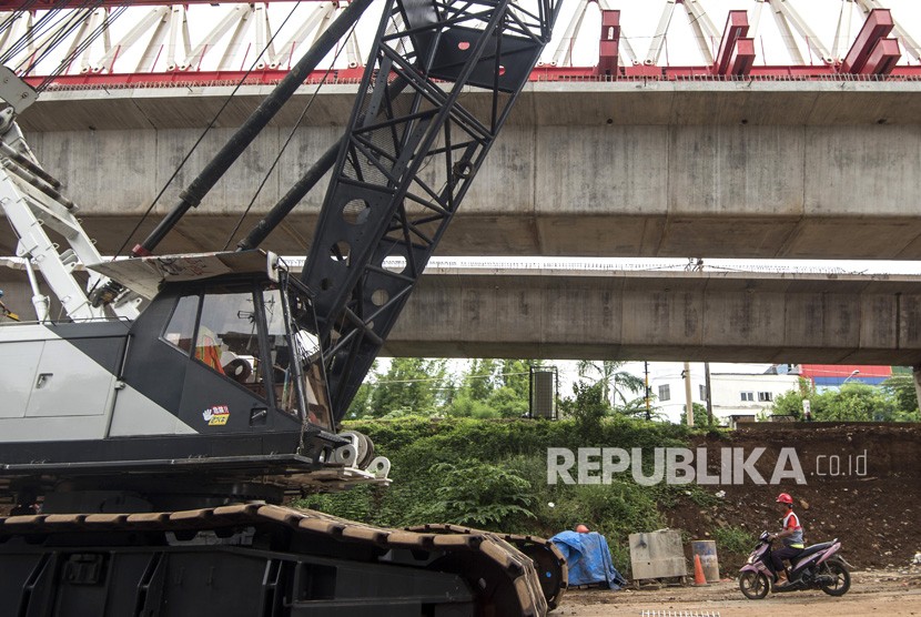 Pekerja melintas di bawah konstruksi jalur rel dwi ganda double-double track di Jakarta Timur, Jumat (2/2).