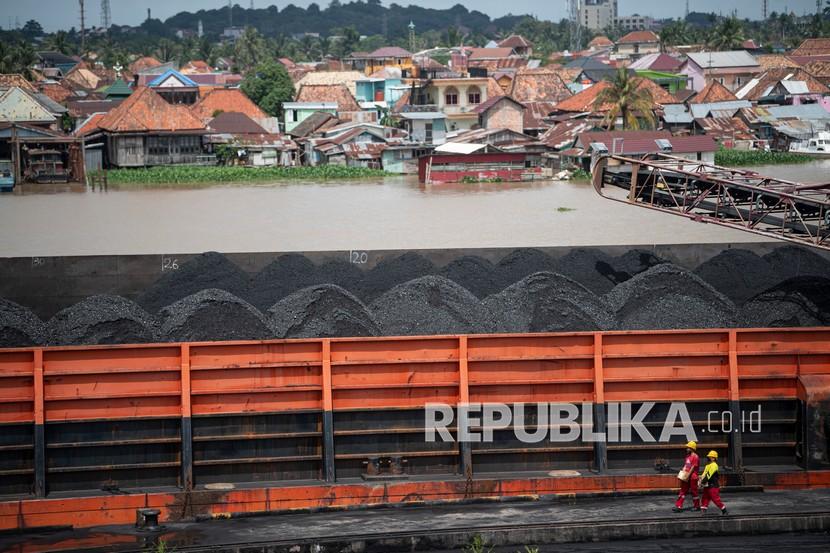 Pekerja melintas di dekat kapal tongkang pengangkut batubara di kawasan Dermaga Batu bara Kertapati milik PT Bukit Asam Tbk di Palembang, Sumatera Selatan, Selasa (4/1/2022). Pemerintah memperbolehkan perusahaan batu bara untuk melakukan ekspor. 