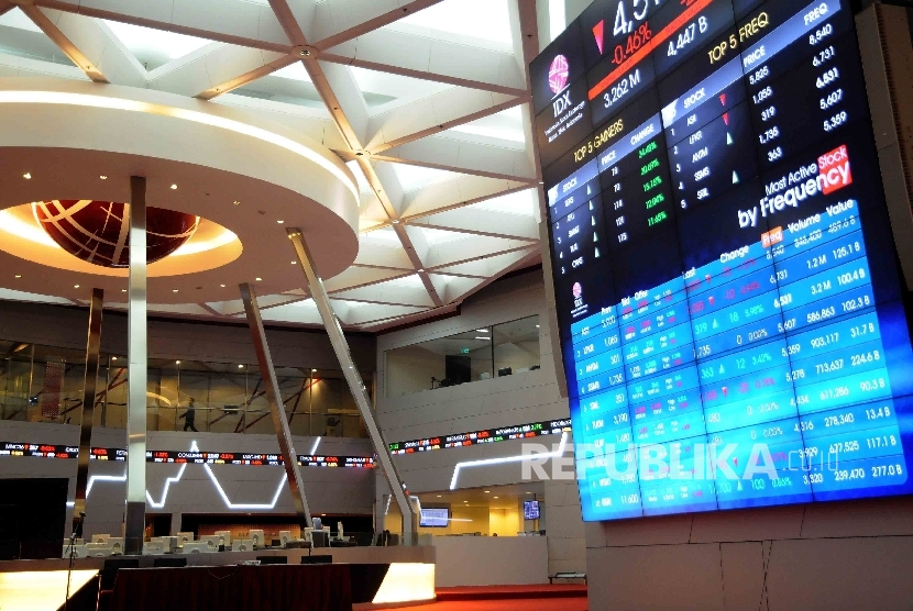 Pekerja melintas di dekat papan monitor pergerakan saham di Bursa Efek Jakarta, Kamis (14/1). Otoritas Jasa Keuangan (OJK) segera menyelesaikan kebijakan yang memungkinkan penerbitan sukuk melalui fintech Equity Crowd Funding (ECF). 