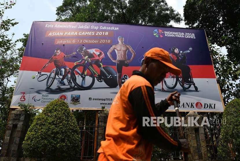 Pekerja melintas di depan baliho sosialisasi Asian Para Games 2018 di Jakarta Selatan, Selasa (24/9).