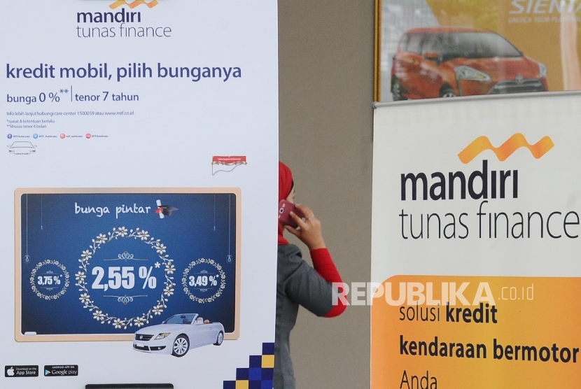  Pekerja melintas dibalik banner penawaran kredit di showroom mobil, Jakarta.