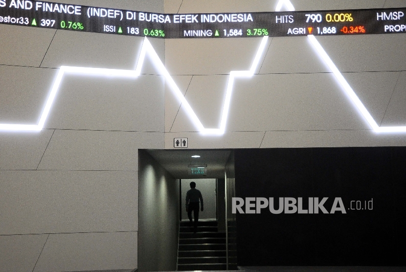 Pekerja melintas didekat layar pergerakan Indeks Harga Saham Gabungan (IHSG) di Gedung Bursa Efek Indonesia (BEI), Jakarta, Selasa (4/4).